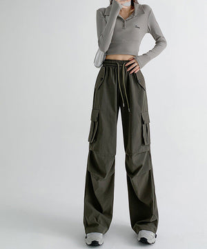 A model wearing a gray long-sleeve cropped polo shirt and olive green wide-leg cargo pants, shown from the neck down against a light gray studio background. Chinese sizing and fit advice text is displayed on the right side.