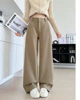 A person wearing beige wide-leg cropped pants and a cream knit sweater stands indoors holding a magazine. The image includes Chinese text on the right side describing the pants as加长款 (longer version) and noting a height recommendation of 164CM and above.