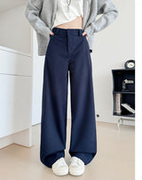 A model wears navy blue wide-leg pants with a white top and a gray cardigan, standing in a minimalist room. The right side of the image features a white panel with Chinese text indicating the color is '藏青' (a dark blue-green) and the pants are '加长款' (longer style), with a height recommendation of 164cm.