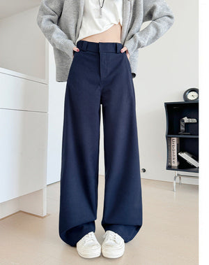 A model wears navy blue wide-leg pants with a white top and a gray cardigan, standing in a minimalist room. The right side of the image features a white panel with Chinese text indicating the color is '藏青' (a dark blue-green) and the pants are '加长款' (longer style), with a height recommendation of 164cm.