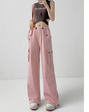A model wears light pink wide-leg cargo pants with a drawstring waist and side pockets, paired with a dark crop top and white sneakers. The image includes a vertical text panel on the right in Chinese describing the color as light pink and noting a height recommendation of 164cm and above.
