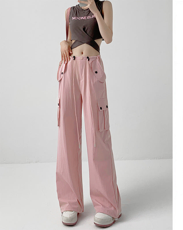 A model wears light pink wide-leg cargo pants with a drawstring waist and side pockets, paired with a dark crop top and white sneakers. The image includes a vertical text panel on the right in Chinese describing the color as light pink and noting a height recommendation of 164cm and above.