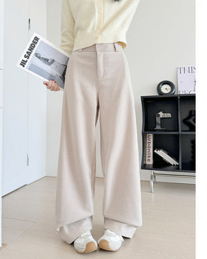 A person wearing light beige wide-leg trousers and a cream cardigan, standing indoors and holding a magazine. The image includes Chinese promotional text on the right side describing the pants as long-leg and recommending a height of 164 cm or above.