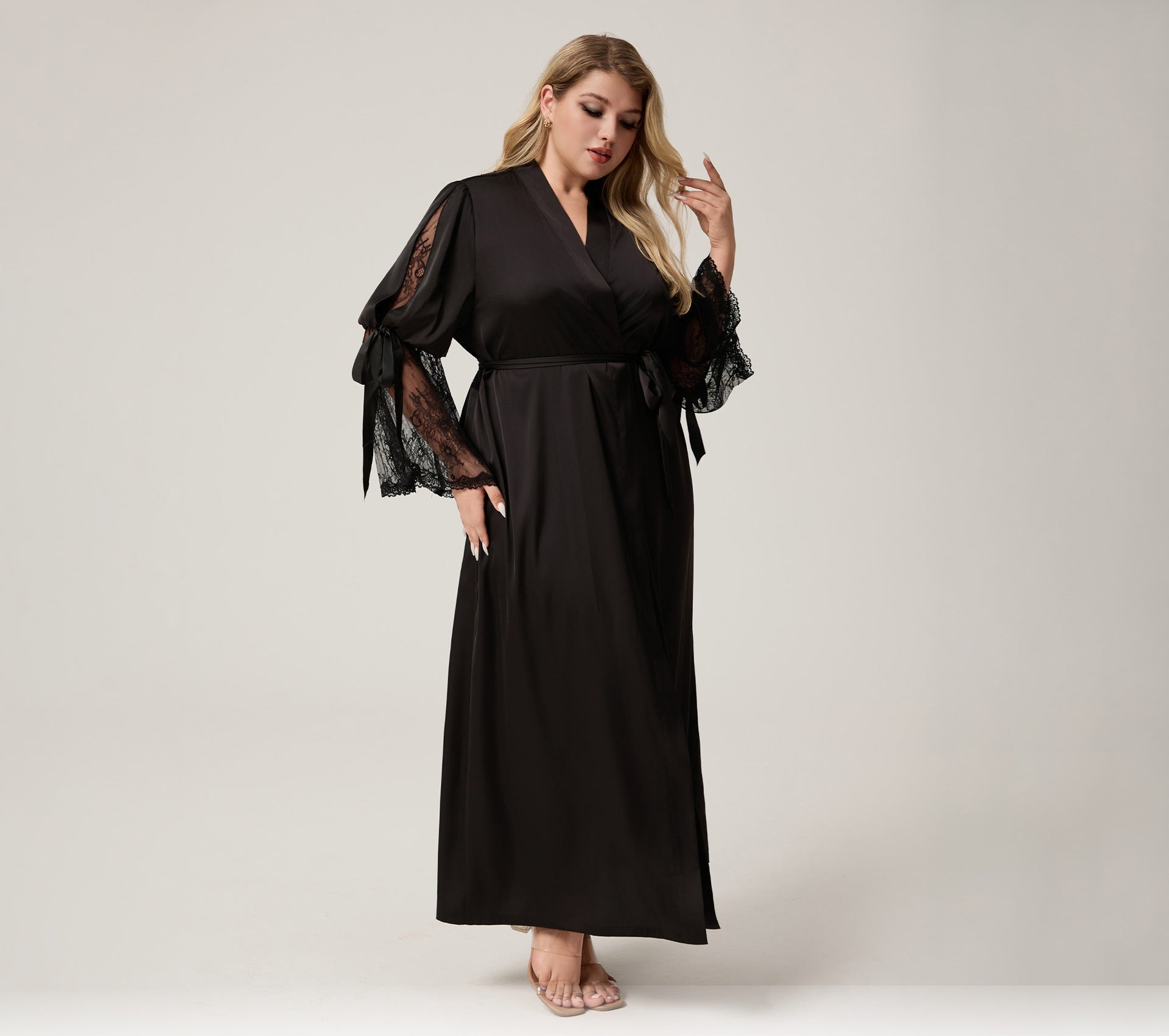 A woman modeling a black maxi wrap dress with sheer black lace flutter sleeves, standing against a light gray studio background. Ozon, Amazon, and wilberries logos are displayed at the bottom.