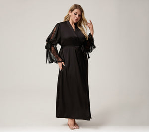 A woman modeling a black maxi wrap dress with sheer black lace flutter sleeves, standing against a light gray studio background. Ozon, Amazon, and wilberries logos are displayed at the bottom.