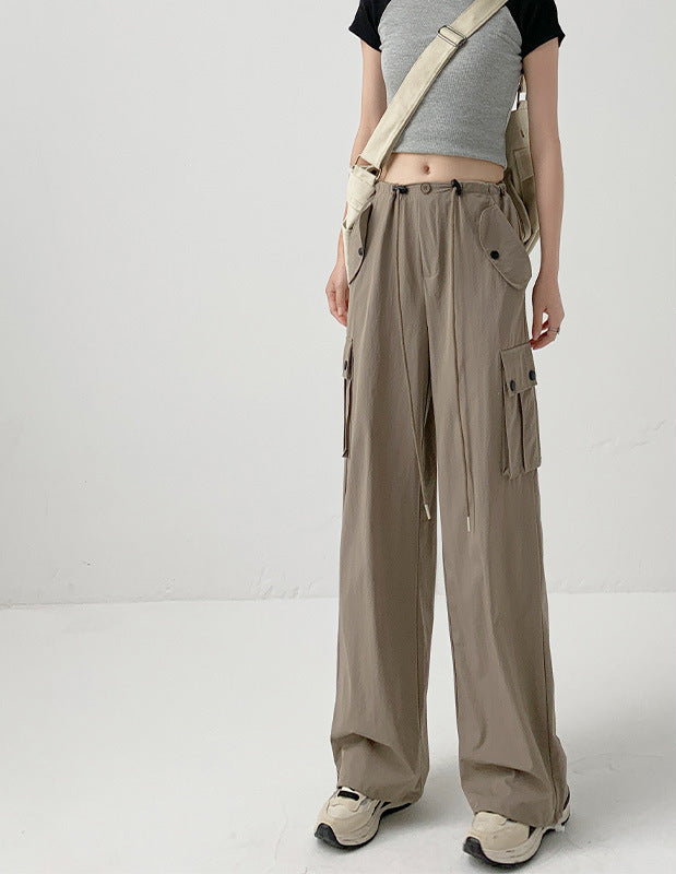 A model wearing wide-leg cargo pants in taupe, styled with a gray crop top, beige crossbody bag, and beige sneakers. The image features a vertical text overlay on the right side with Chinese text describing the product details.